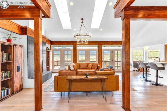 living room with french doors, a chandelier, sink, and light wood-type flooring