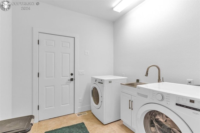 clothes washing area featuring cabinets, washer and clothes dryer, sink, and light tile patterned floors