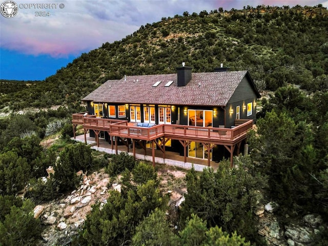 back house at dusk with a wooden deck