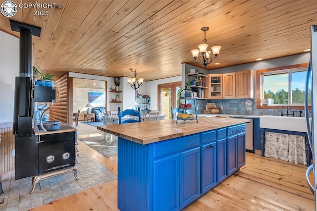 kitchen featuring blue cabinetry, open shelves, butcher block counters, light wood-style flooring, and a chandelier