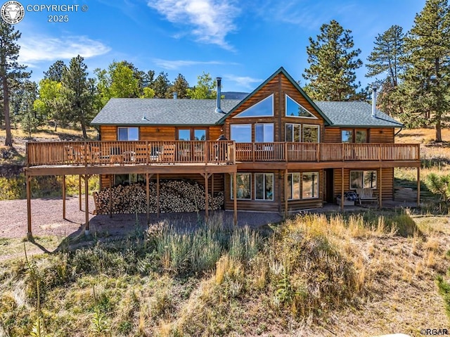 back of house featuring a shingled roof and a wooden deck