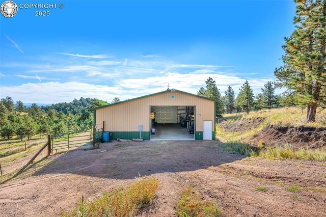 view of pole building featuring fence and dirt driveway