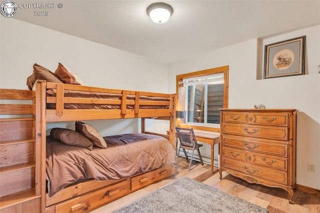 bedroom with baseboard heating and wood finished floors