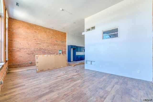 spare room featuring hardwood / wood-style floors, a high ceiling, and brick wall