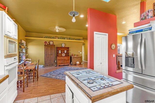 kitchen with white cabinetry, white appliances, pendant lighting, and light tile patterned flooring