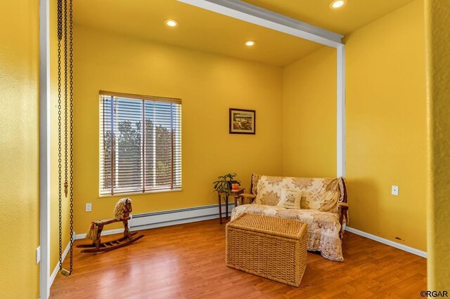 sitting room featuring a baseboard heating unit and hardwood / wood-style floors