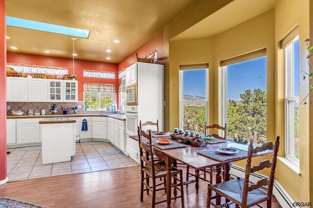 dining room with a skylight and light tile patterned flooring