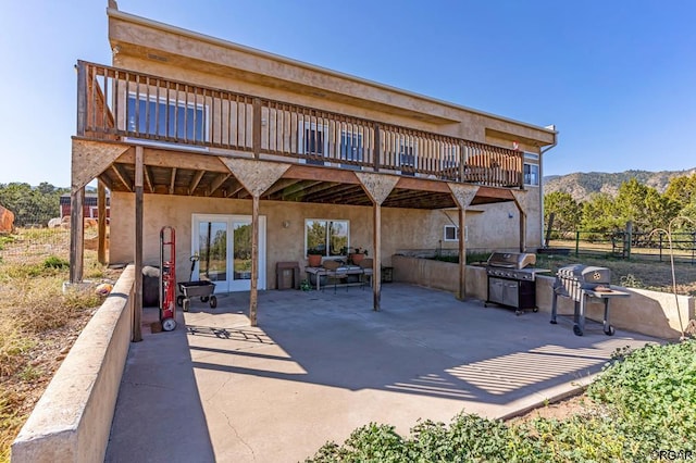 back of house with french doors, a deck with mountain view, and a patio