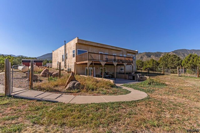 rear view of house featuring a deck with mountain view and a lawn