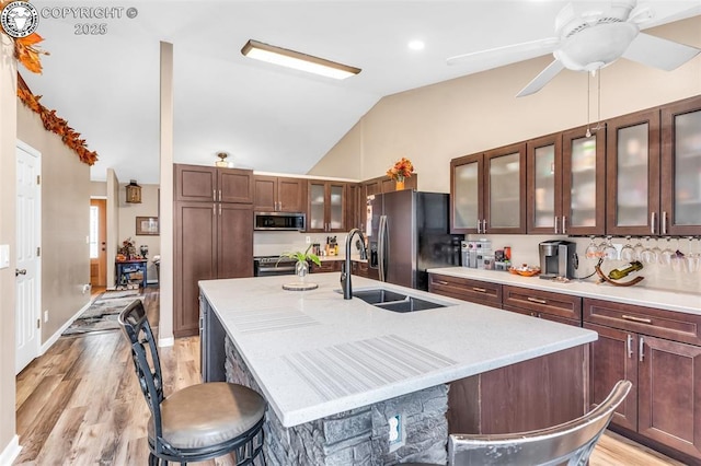 723 Griffin Ave, Canon City, CO 81212 - kitchen featuring appliances with stainless steel finishes, a center island with sink, lofted ceiling, a kitchen bar, and light wood-style flooring