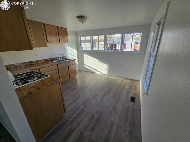 kitchen with dark hardwood / wood-style flooring, sink, and white gas stovetop