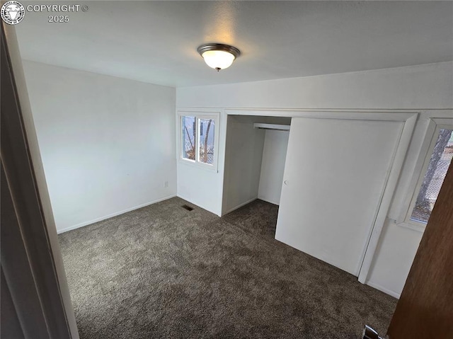 unfurnished bedroom with dark carpet and a closet