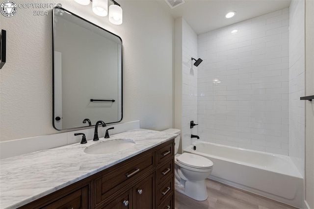 full bathroom featuring tiled shower / bath, hardwood / wood-style floors, vanity, and toilet