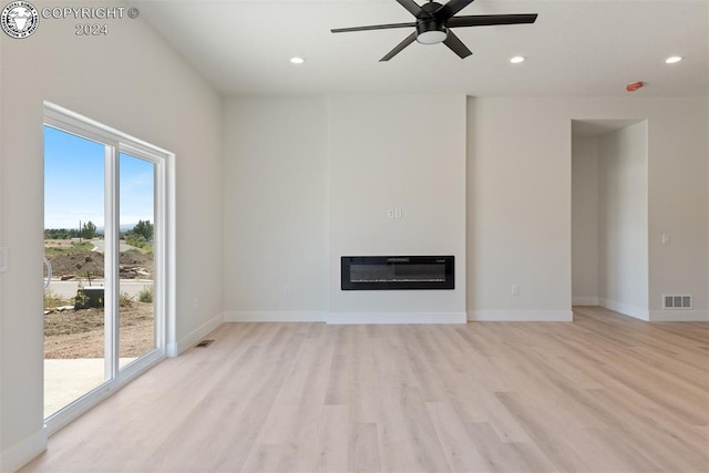 unfurnished living room featuring ceiling fan, heating unit, and light hardwood / wood-style floors