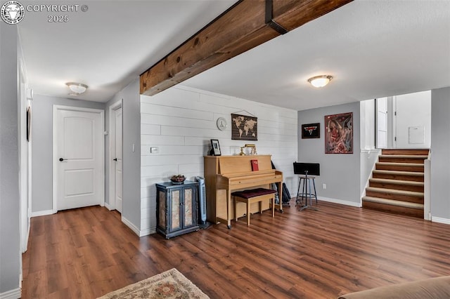 miscellaneous room with dark wood-type flooring, beam ceiling, and wood walls