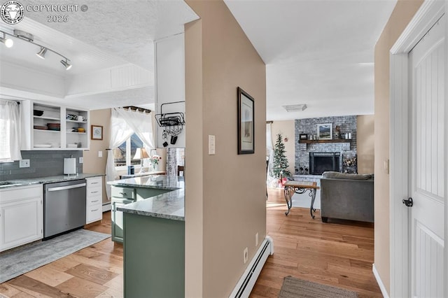 kitchen featuring a fireplace, green cabinets, stainless steel dishwasher, baseboard heating, and light hardwood / wood-style flooring