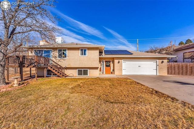 view of front of home with a garage, a deck, a front lawn, and solar panels