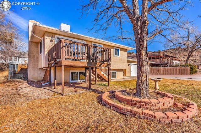 rear view of house with a garage, a deck, and a lawn