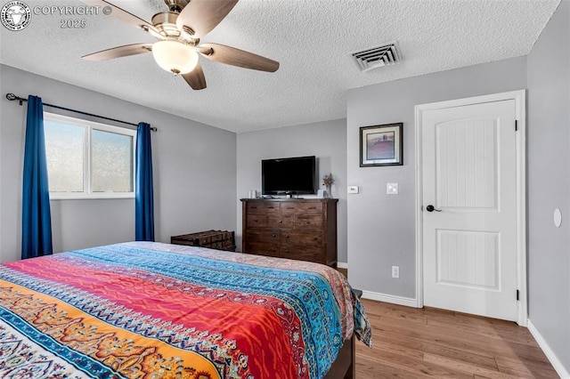 bedroom featuring a textured ceiling, ceiling fan, and light hardwood / wood-style floors