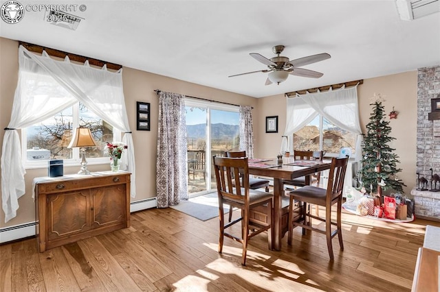 dining area featuring baseboard heating, ceiling fan, a mountain view, and light hardwood / wood-style flooring