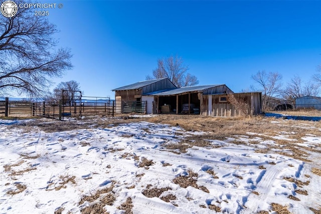 snow covered back of property with an outdoor structure