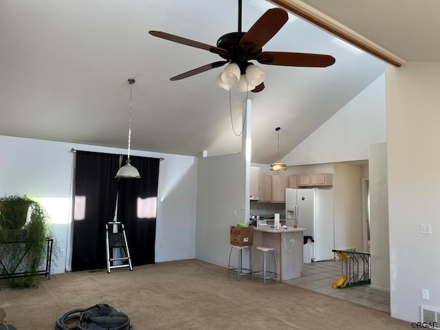 kitchen with hanging light fixtures, white fridge with ice dispenser, a kitchen bar, light brown cabinetry, and light colored carpet