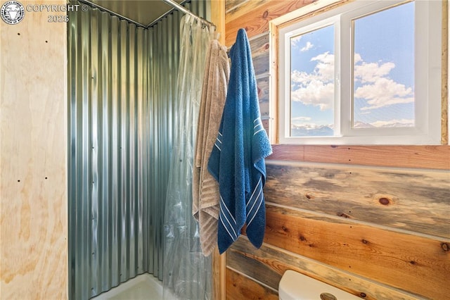 bathroom with toilet, wooden walls, and walk in shower