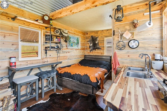 bedroom featuring sink, beamed ceiling, and wood walls