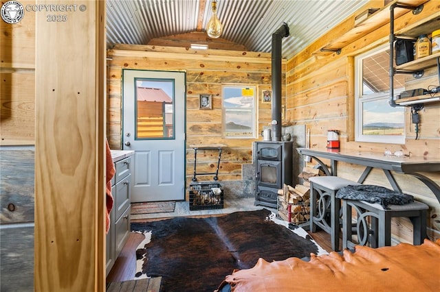 interior space featuring vaulted ceiling, a wood stove, and wood walls