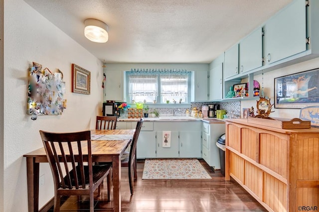 kitchen featuring blue cabinets, sink, a textured ceiling, and dark hardwood / wood-style floors