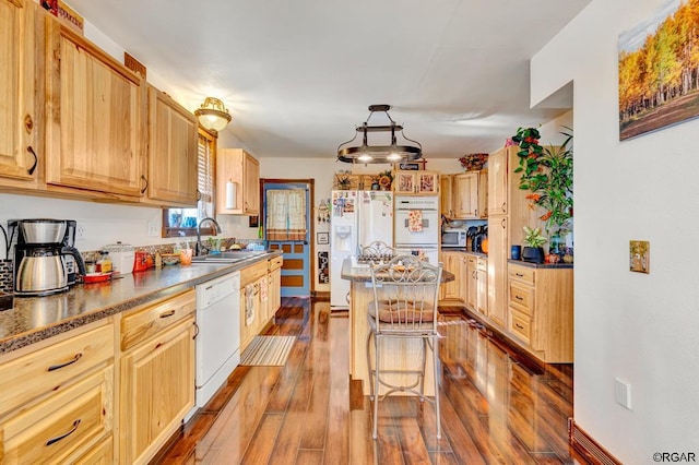 kitchen with a breakfast bar, sink, light brown cabinets, pendant lighting, and white appliances