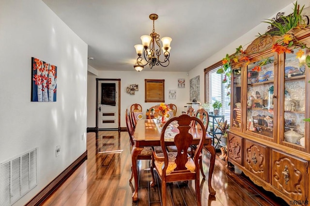 dining space with dark hardwood / wood-style floors and a chandelier