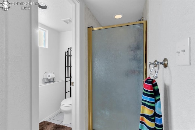 bathroom featuring tile patterned flooring, a shower with door, and toilet