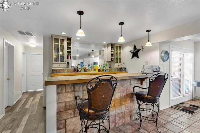 bar featuring pendant lighting, light hardwood / wood-style floors, and butcher block countertops