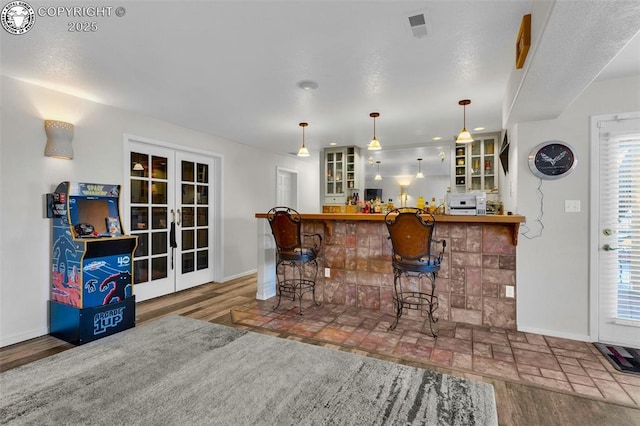 bar with french doors, hardwood / wood-style floors, and pendant lighting