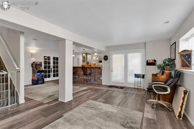 interior space with hardwood / wood-style floors, french doors, and bar area