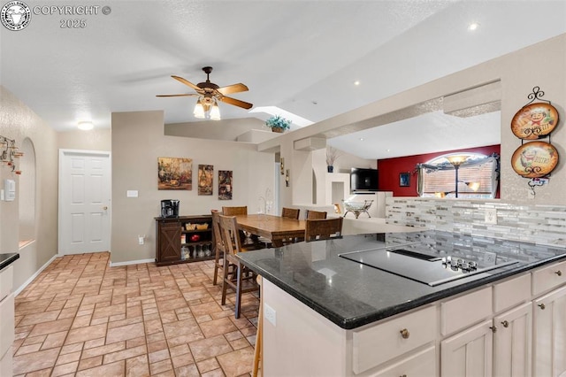 kitchen featuring ceiling fan, white cabinetry, dark stone countertops, tasteful backsplash, and black electric stovetop