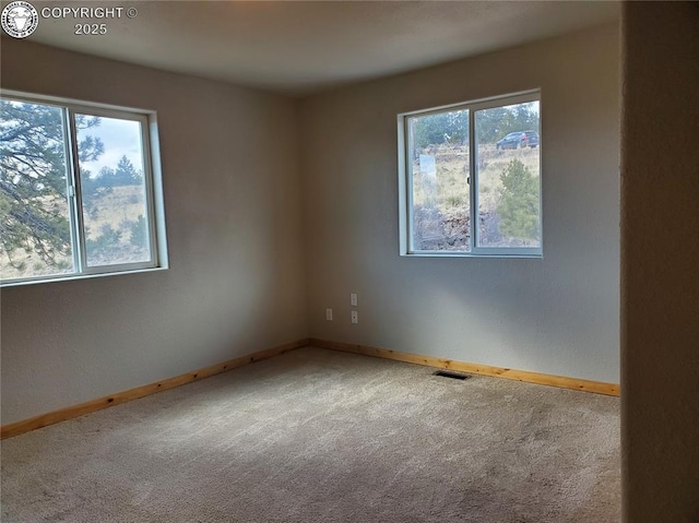 unfurnished room with carpet, visible vents, and baseboards