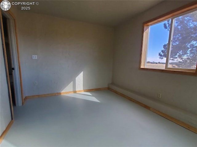 unfurnished room featuring concrete floors and baseboards