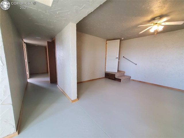 below grade area featuring baseboards, stairway, and ceiling fan