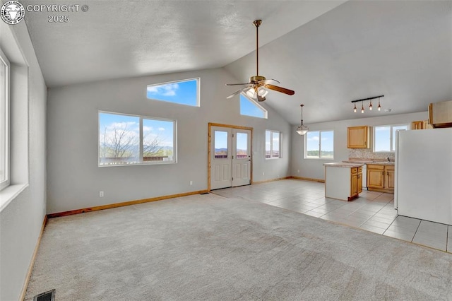 180 E Cobb Ln, Guffey, CO 80820 - unfurnished living room with light tile patterned floors, a ceiling fan, visible vents, light carpet, and lofted ceiling