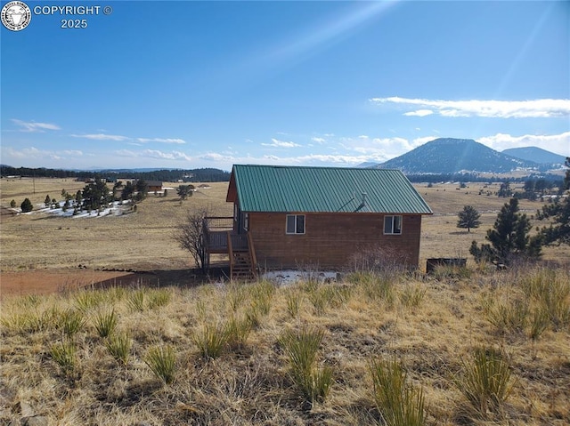 view of property exterior with a mountain view, metal roof, and a rural view