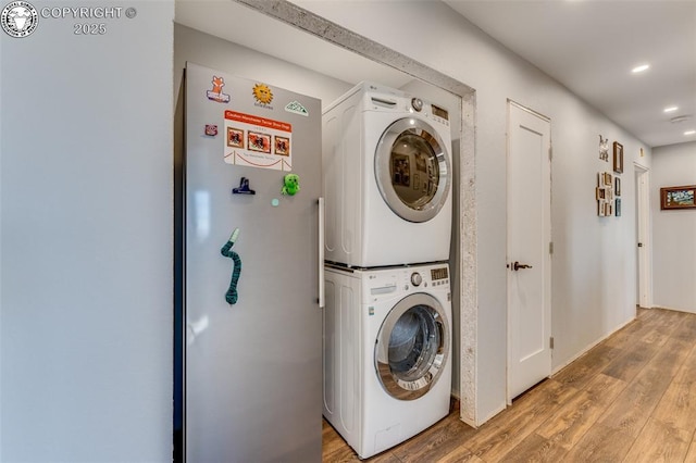 washroom with hardwood / wood-style flooring and stacked washer / dryer