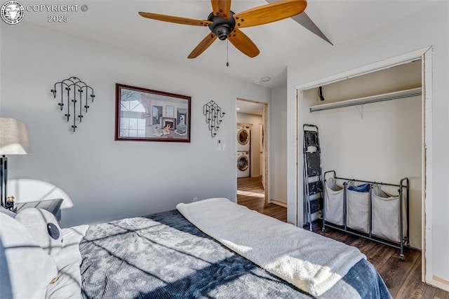 bedroom featuring ceiling fan, stacked washer / dryer, dark hardwood / wood-style flooring, and a closet