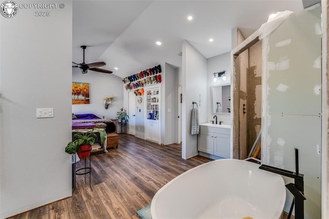 bathroom with lofted ceiling, a bathing tub, wood-type flooring, and vanity