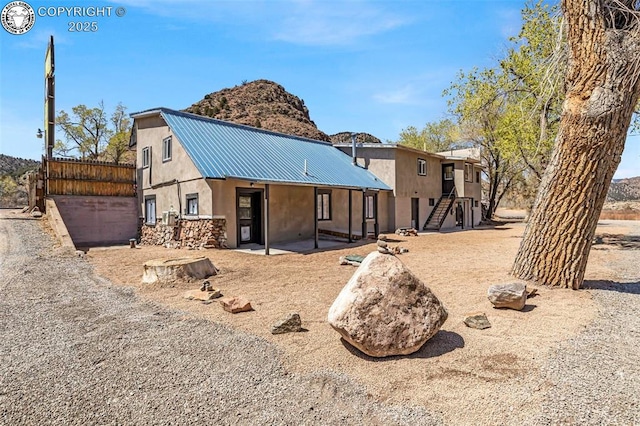 back of property featuring stucco siding, a patio area, and metal roof