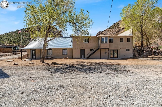 rear view of house featuring metal roof and stucco siding