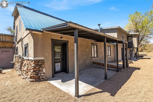 back of property featuring stucco siding, fence, metal roof, and a patio area