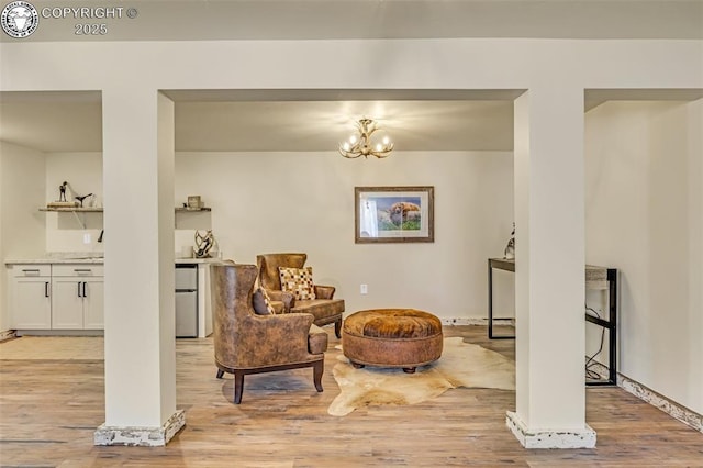 sitting room featuring an inviting chandelier, light wood-style floors, and baseboards