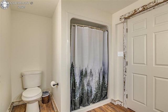 full bath featuring curtained shower, toilet, baseboards, and wood finished floors